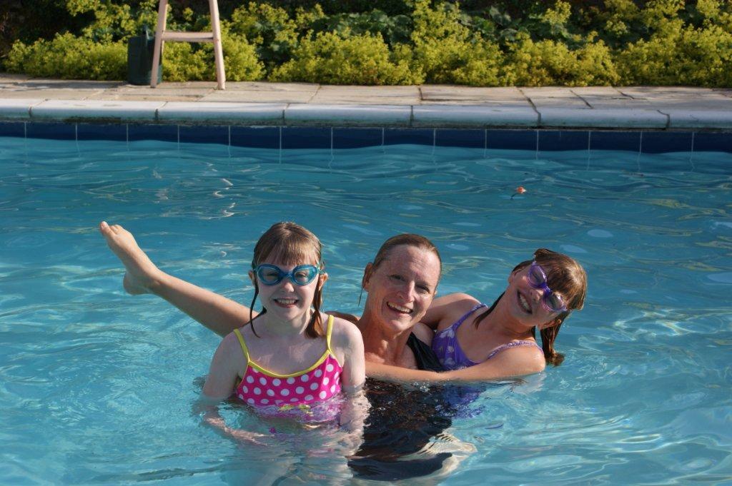 Happy holiday guests in outdoor swimming pool at Byre Cottages, Sullington Manor Farm, West Sussex, RH20 4AE. Self catering holiday cottages in South Downs countryside